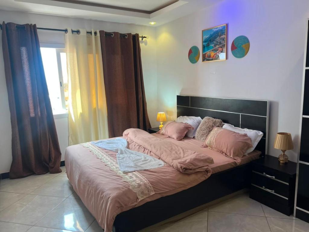 a bedroom with a large bed with pink sheets and pillows at Adja Adama sow in Dakar
