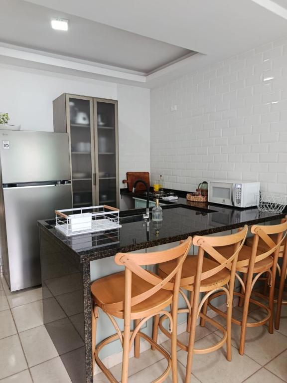 a kitchen with a counter with chairs and a refrigerator at Casa em Sorocaba para até 4 pessoas in Sorocaba