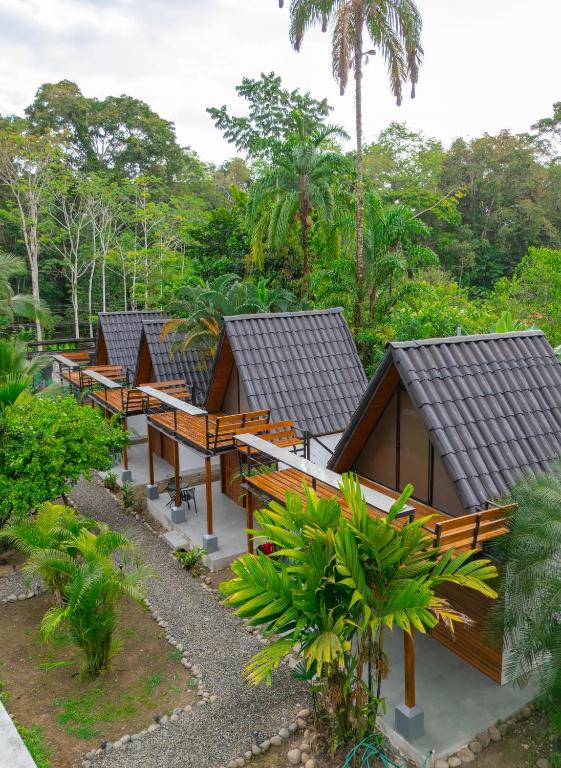 a row of resort huts with benches and trees at Sloth Bungalows Manzanillo in Manzanillo