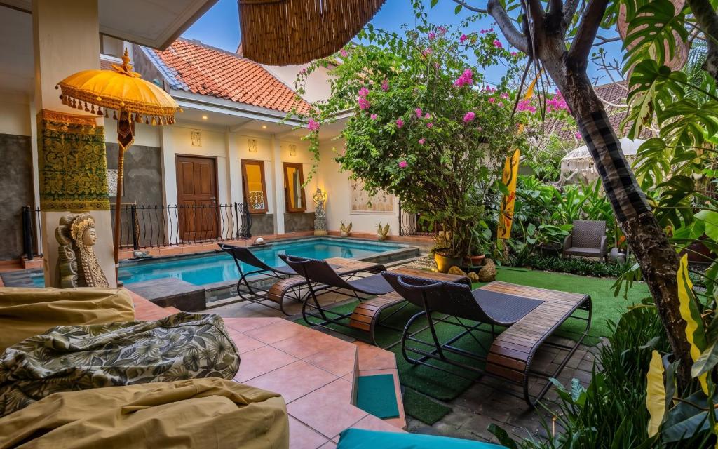 a backyard with a pool and chairs and a house at GWK View Boutique Hotel and Serviced Residence in Jimbaran