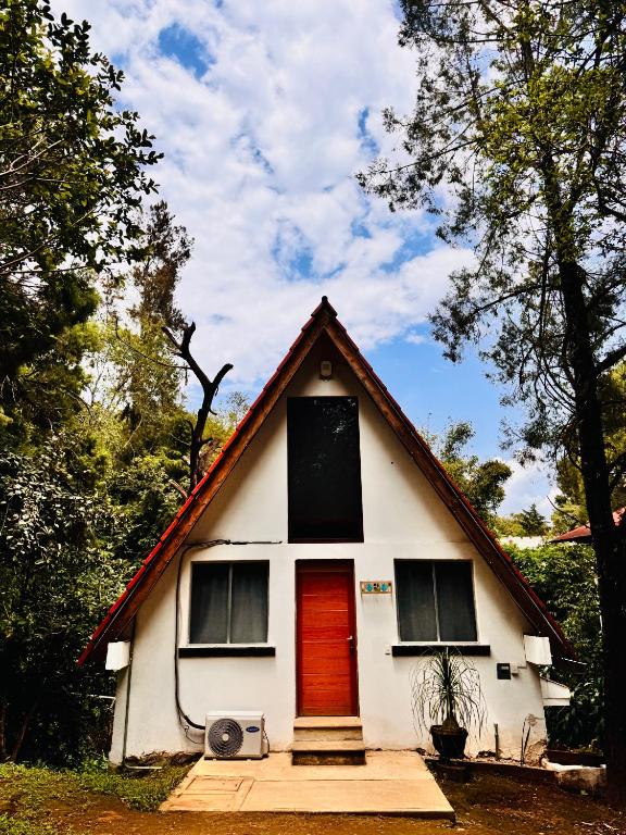 a small white house with a red door at La cabaña del jaguar in Tepoztlán