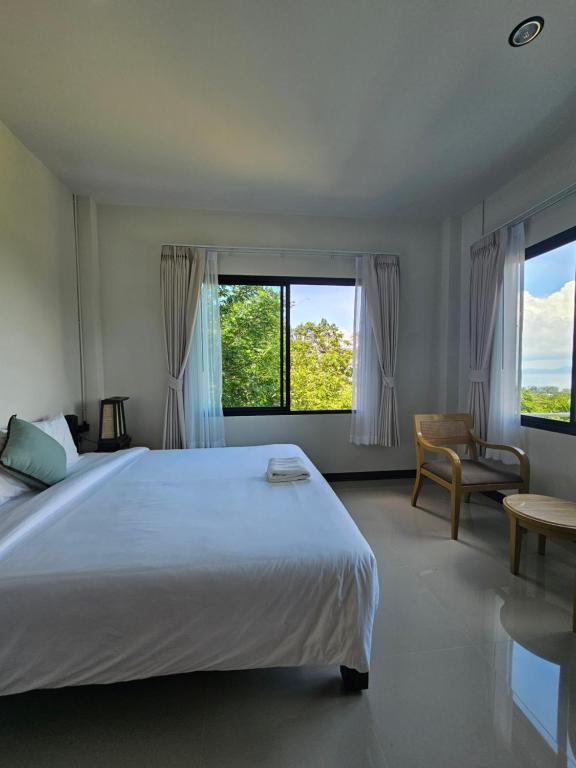 a bedroom with a large white bed and a chair at Anda Sea view in Klong Muang Beach