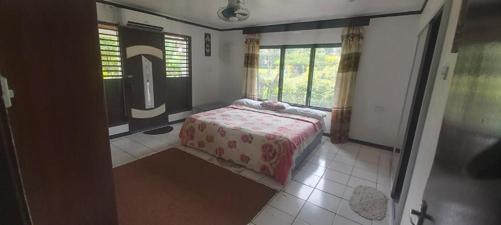a bedroom with a bed in a room with windows at Ali's Homestay in Pacific Harbour