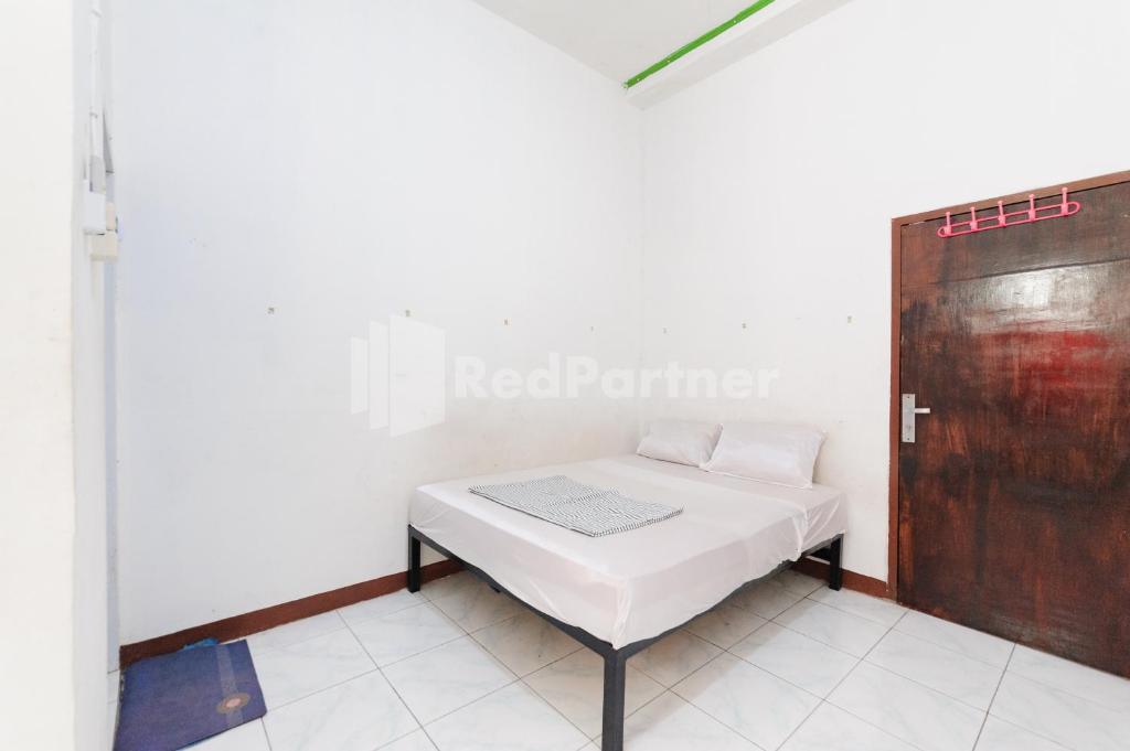a room with a bed and a wooden door at Ombai Guest House 27 Syariah Mitra RedDoorz in Kertapati