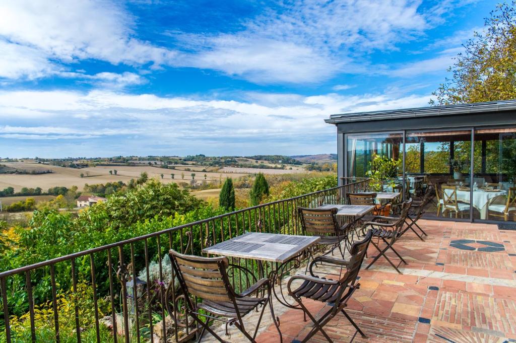 un patio con tavoli e sedie su un balcone di Cuq en Terrasses a Cuq-Toulza