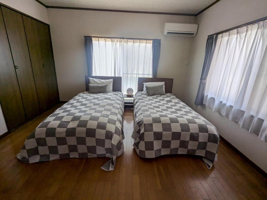 zwei Betten in einem Zimmer mit zwei Fenstern in der Unterkunft Episode1 in Naoshima