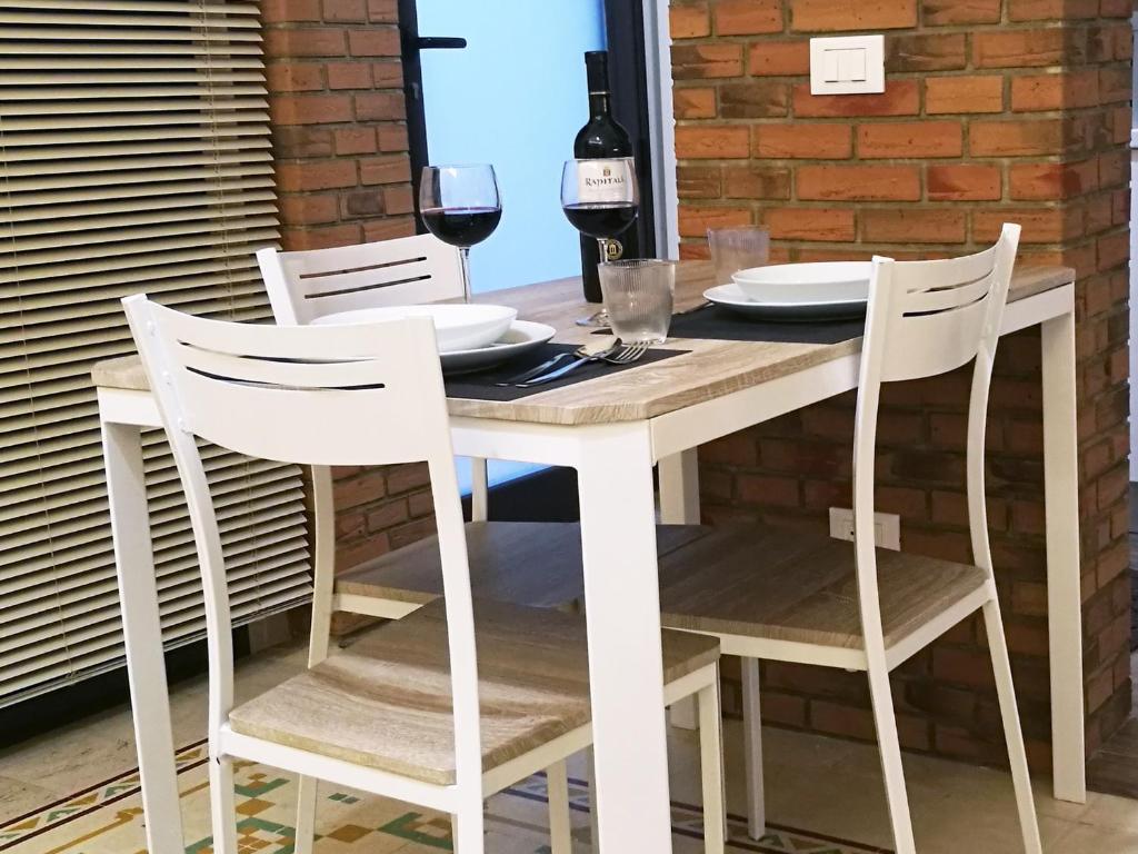 トラーパニにあるPrimo Piano Riccio Locazione Turisticaの木製テーブル(白い椅子、ワイングラス付)