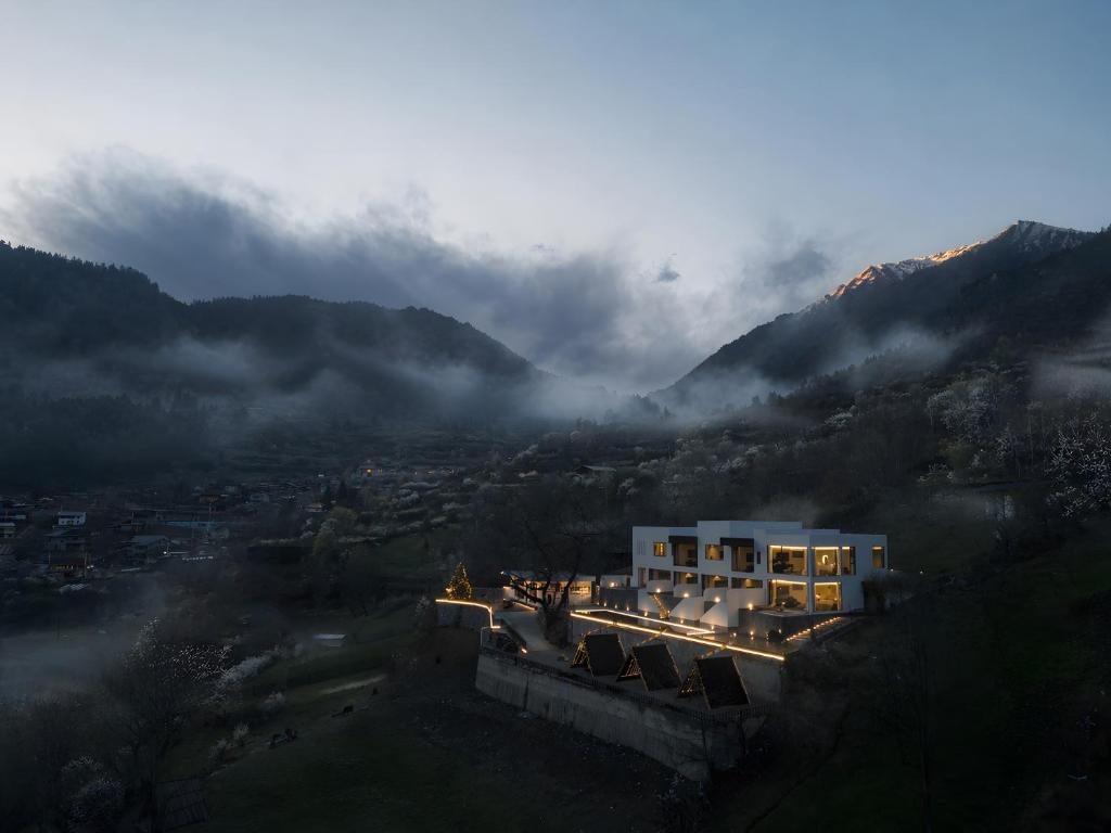 a building on a hill with mountains in the background at NINE PEAKS in Jiuzhaigou