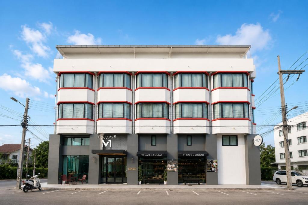 a large white building with a clock on a street at V1 boutique hotel in Kanchanaburi City