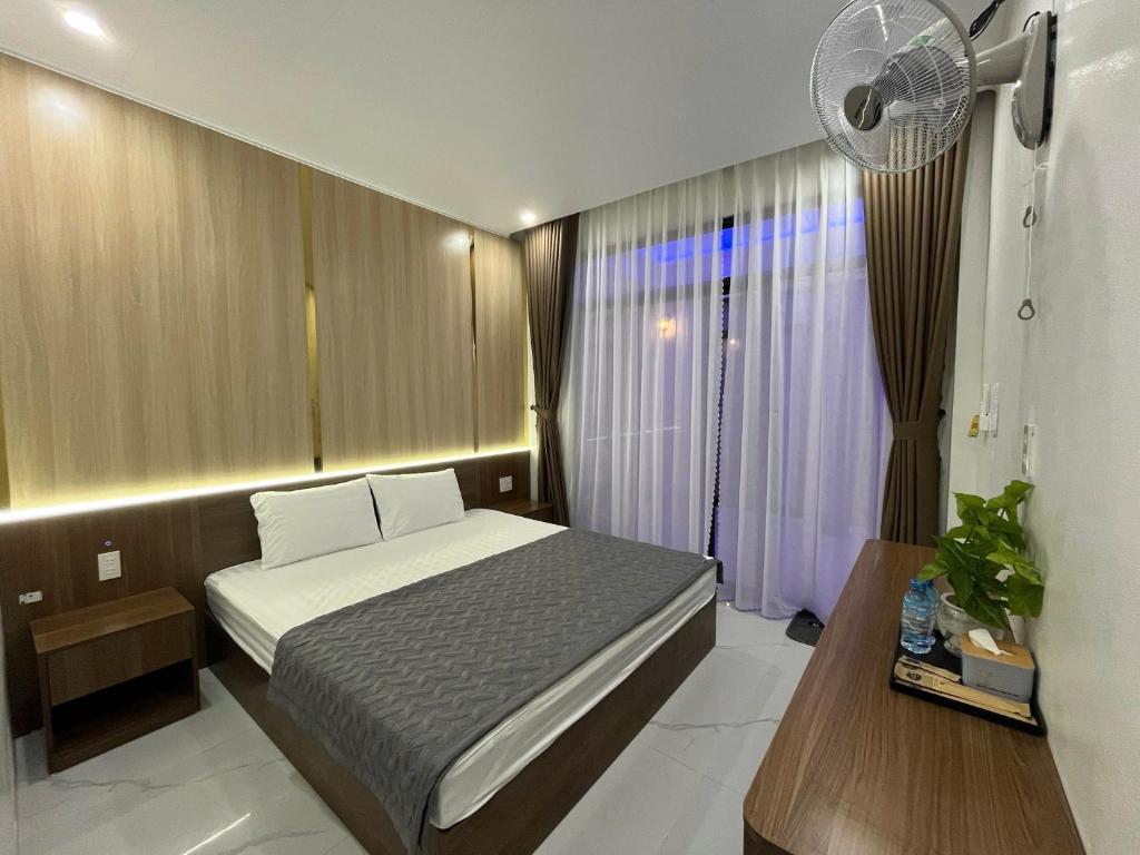 a small bedroom with a bed and a fan at Hải Đảo Homestay in Quan Lạn