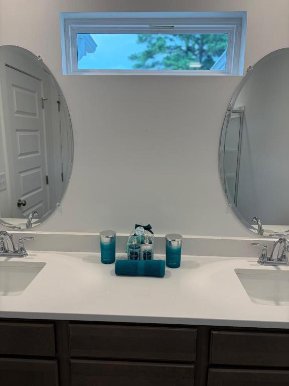 a bathroom with two sinks and two mirrors at Modern Comfort in Morrow