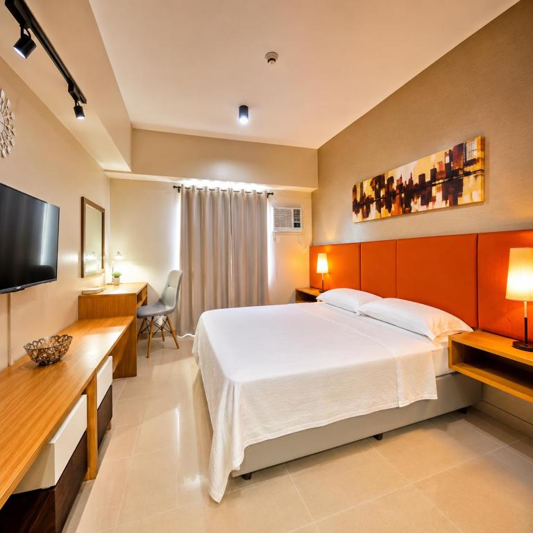 a bedroom with a bed and a desk and a television at MIGAs Haven at Sunvida Tower across SM City in Cebu City