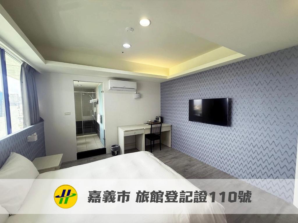 a bedroom with a bed and a tv on a wall at 勤天行旅-嘉義站前 in Chiayi City