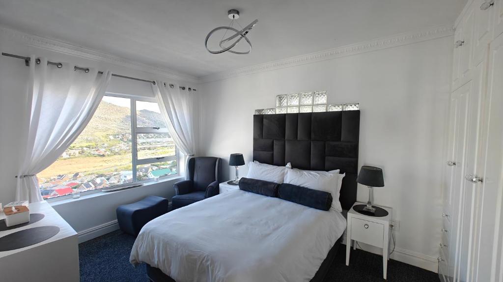 a bedroom with a bed and a chair and a window at Executive Sea View Apartment in Glencairn