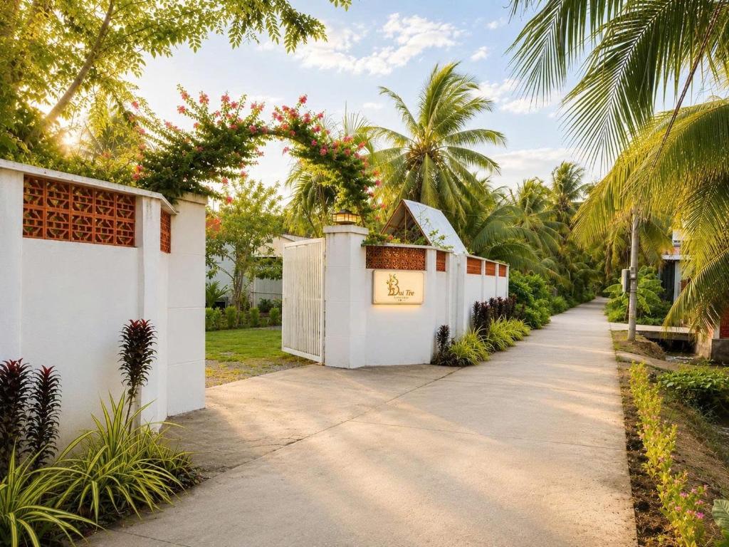 a driveway with a white fence and palm trees at Bụi Tre Homestay in Ben Tre