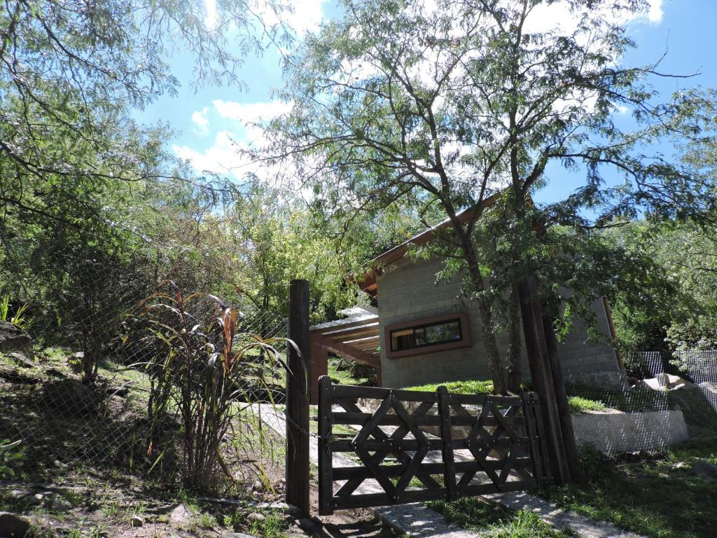 a fence in front of a house with a tree at Cabañas La Joaquina in Río Ceballos