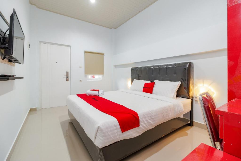 a bedroom with a bed with a red blanket on it at RedDoorz Plus near Palembang Icon Mall 2 in Palembang