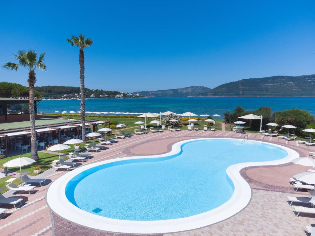 ein Schwimmbad mit Liegestühlen und Sonnenschirmen und das Meer in der Unterkunft Hotel Corte Rosada - Adults Only, Affiliated by Meliá in Porto Conte