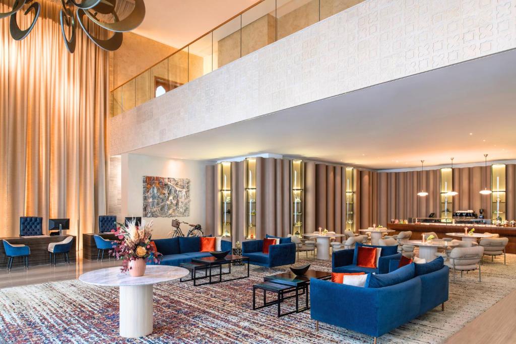 a hotel lobby with blue couches and tables at Abesq Doha Hotel and Residences, an IHG Hotel in Doha