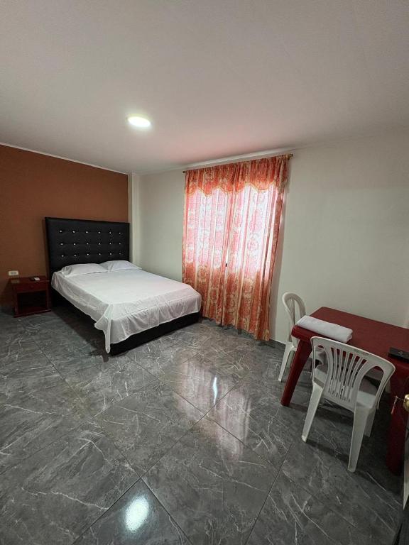 a bedroom with a bed and a table and a window at Hospedaje Hotel Chone in Chone
