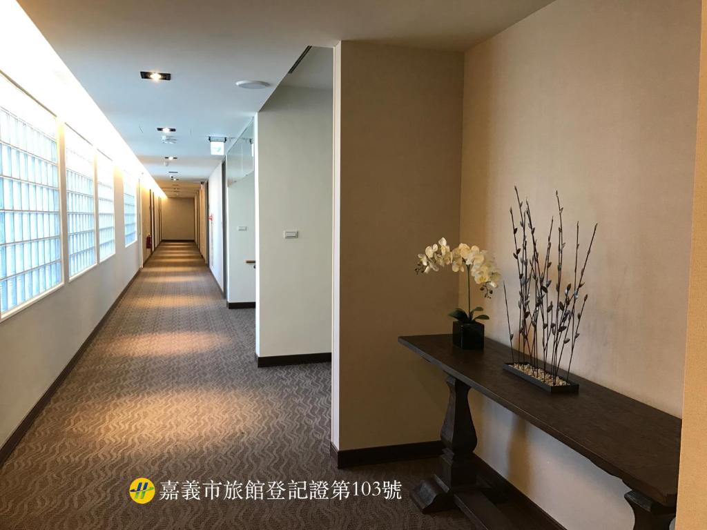 ein Flur mit einem langen Korridor, auf dem ein Tisch und Blumen stehen. in der Unterkunft ML Hotel in Chiayi
