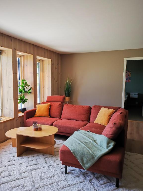 a living room with a red couch and a table at Lofoten Seaview Apartment B in Sennesvik