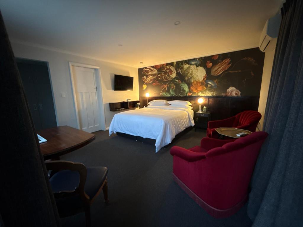 a hotel room with a bed and two chairs at Art Deco BNB in Havelock North