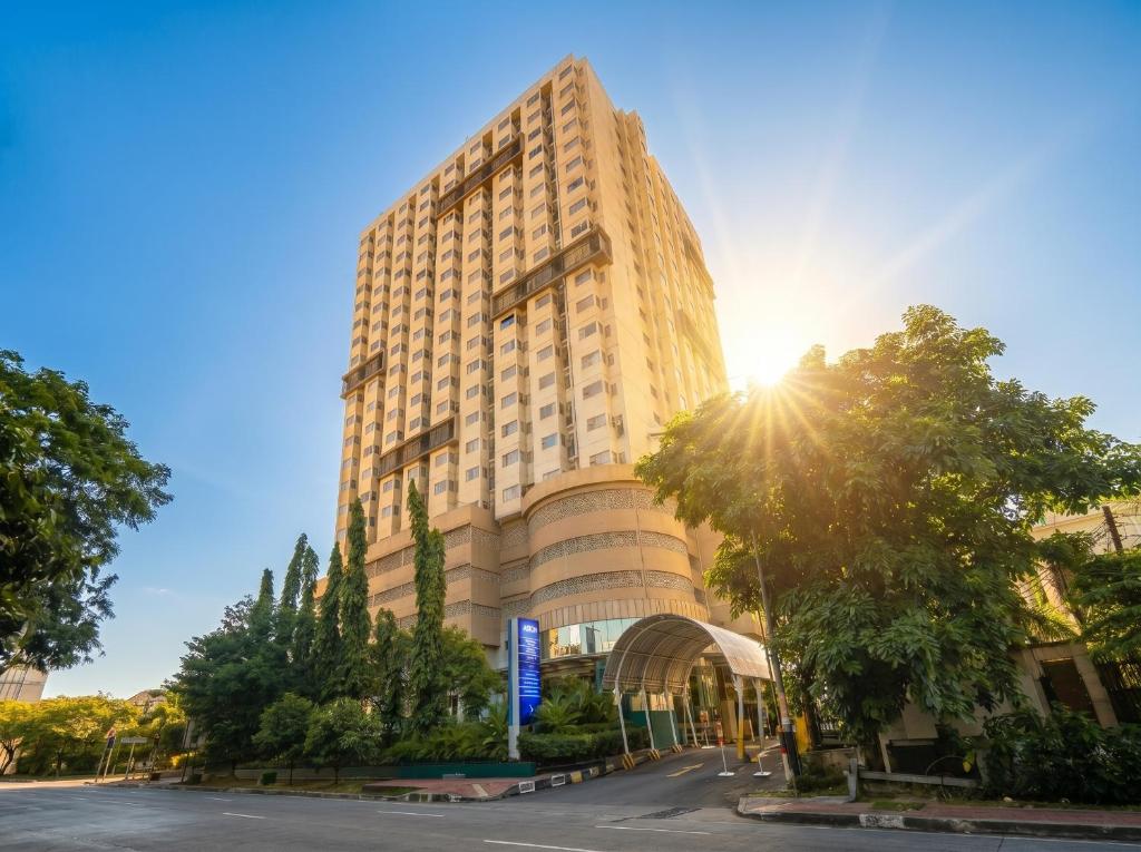 a tall building with the sun shining on it at ASTON Pluit Hotel & Residence in Jakarta