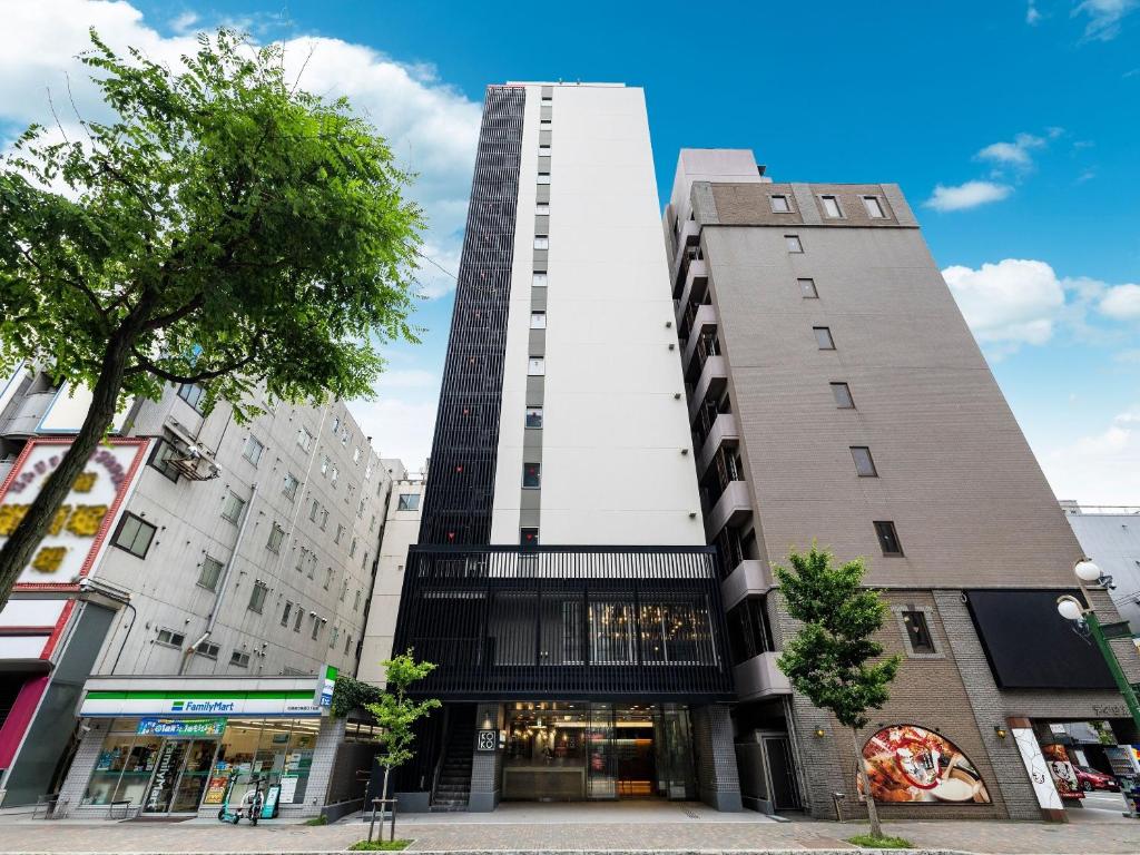 a tall building on a city street with buildings at KOKO HOTEL Sapporo Susukino 2ⁿᵈ in Sapporo