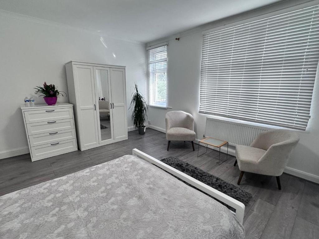 a bedroom with a dresser and two chairs and a bed at Watford Junction Stay in Watford