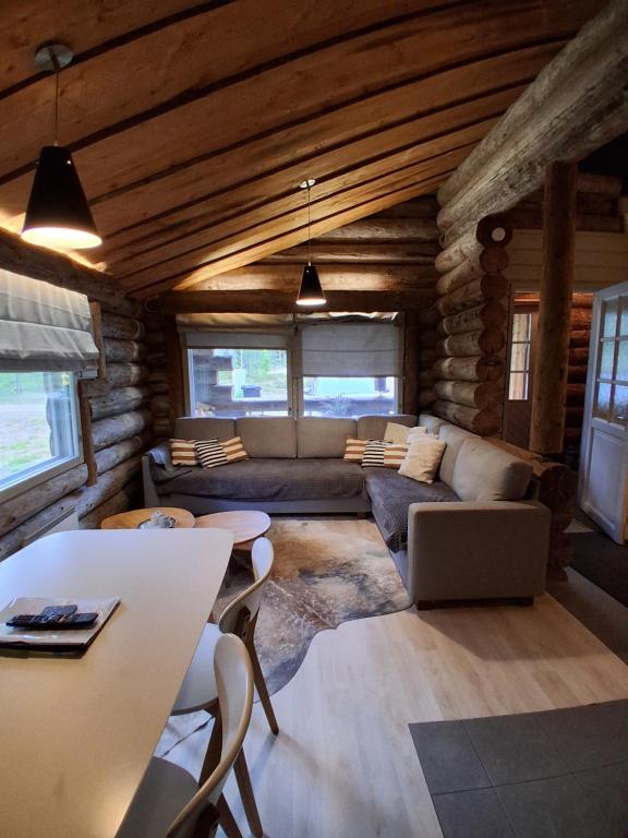 a living room with a couch and a table at Iso-Syöte tunnelmallinen kelomökki in Naamanka