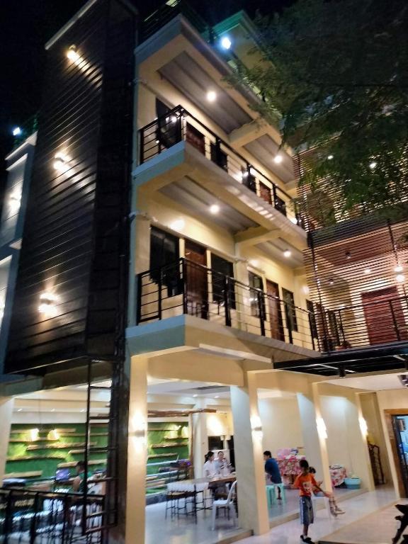 a building with people standing outside of it at night at W Island Backpackers Inn in Dauis