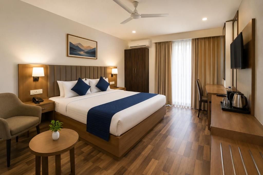 a hotel room with a large bed and a chair at JHS Kundli in Sonīpat
