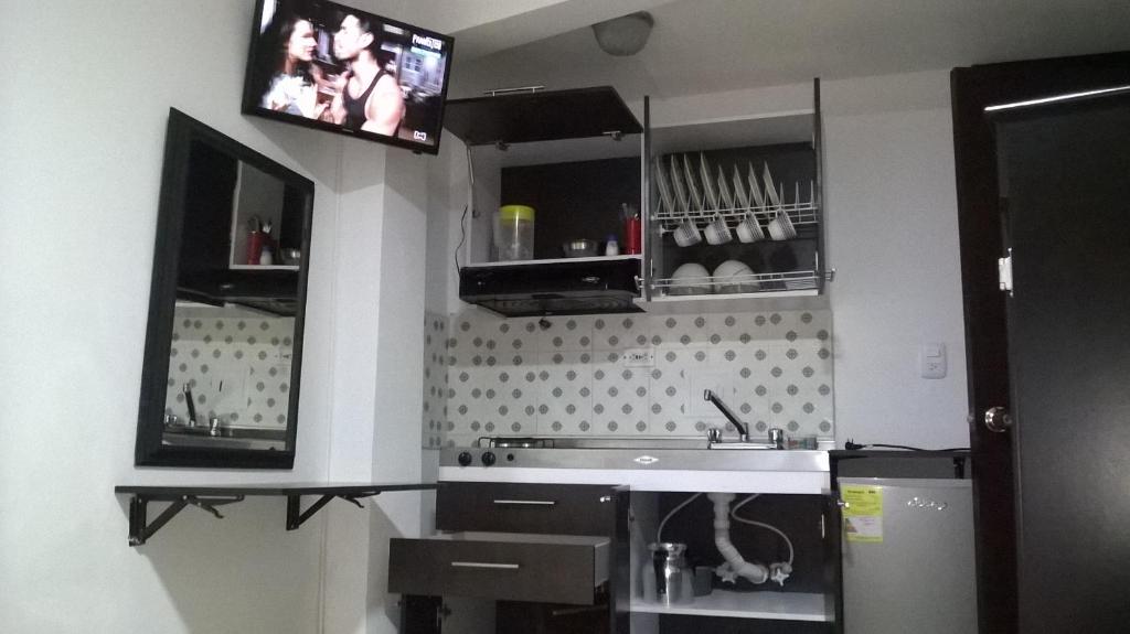a kitchen with a sink and a tv on the wall at Apartaestudios El Cable in Manizales