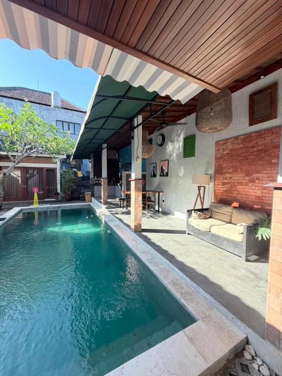 an outdoor swimming pool with a patio and an umbrella at Sutji living in Sanur