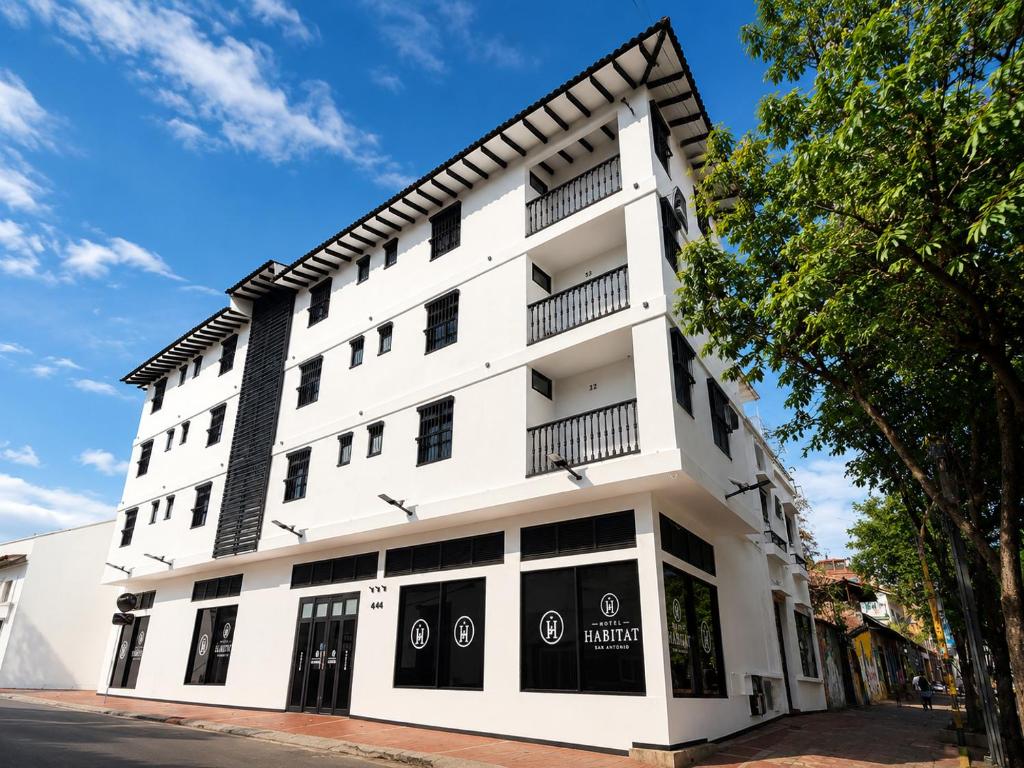 a white building with black windows on a street at Hotel Habitat San Antonio in Cali