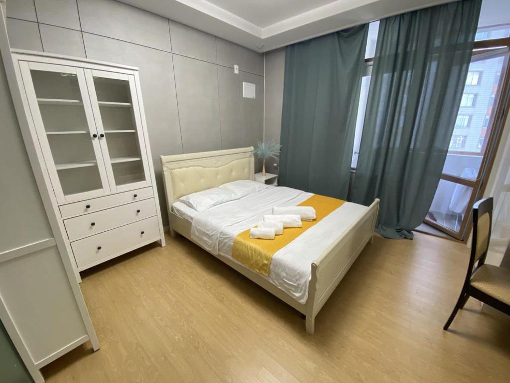 a bedroom with a bed and a cabinet and a chair at Wh in HighVill in Astana