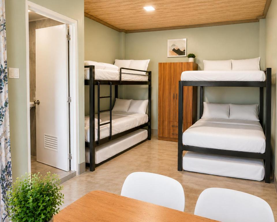 a room with three bunk beds with a table and chairs at Casa Amul in Tigbawan
