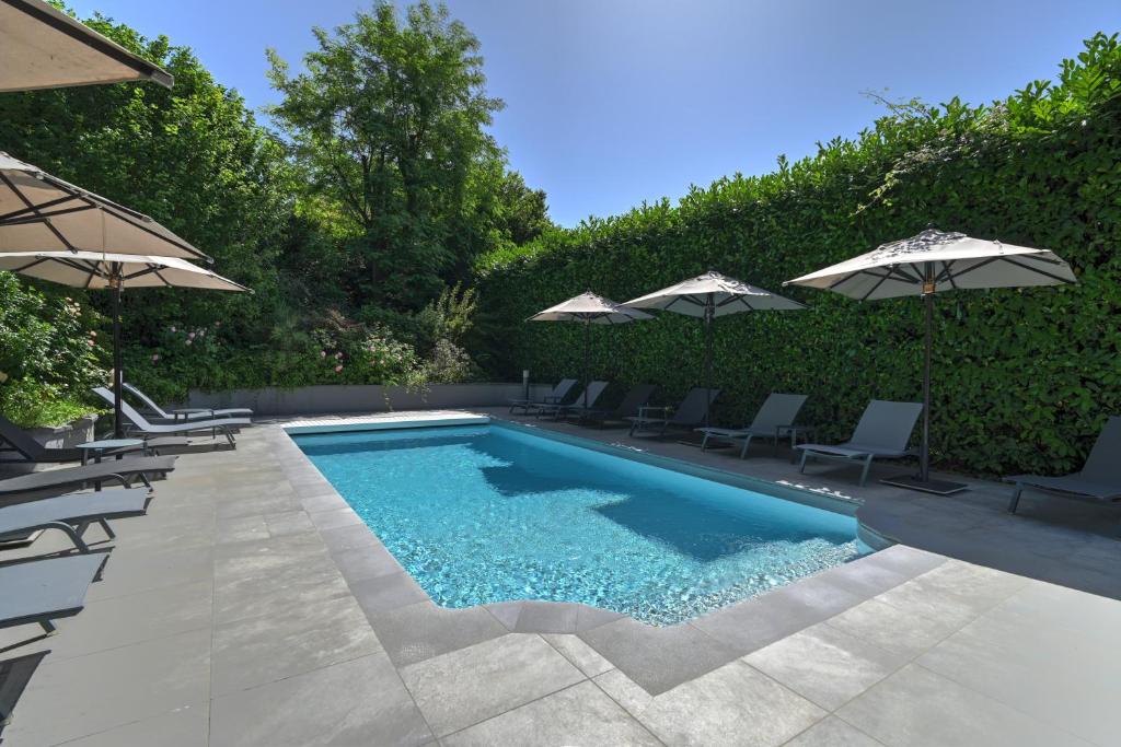 a swimming pool with chairs and umbrellas at Logis Hotel Le Petit Casset in La Boisse