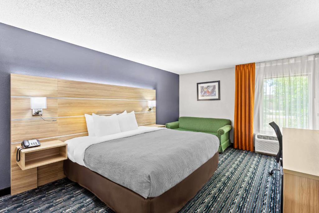 a hotel room with a bed and a green couch at Quality Inn Rochester South in Rochester