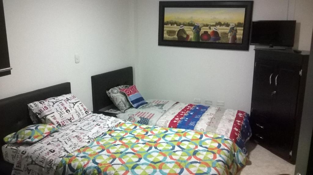 ein Schlafzimmer mit einem Bett und einem Bild an der Wand in der Unterkunft Apartaestudios El Cable in Manizales