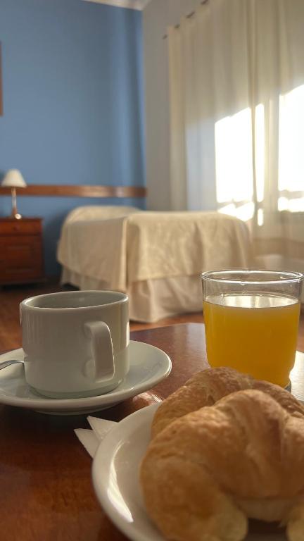 a table with a plate of bread and a cup of orange juice at Manantiales Hotel Boutique in Victoria