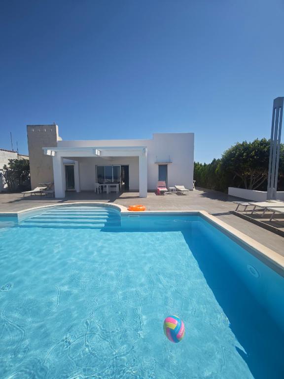 a swimming pool with a ball in front of a house at B&B Torrefano in Portopalo