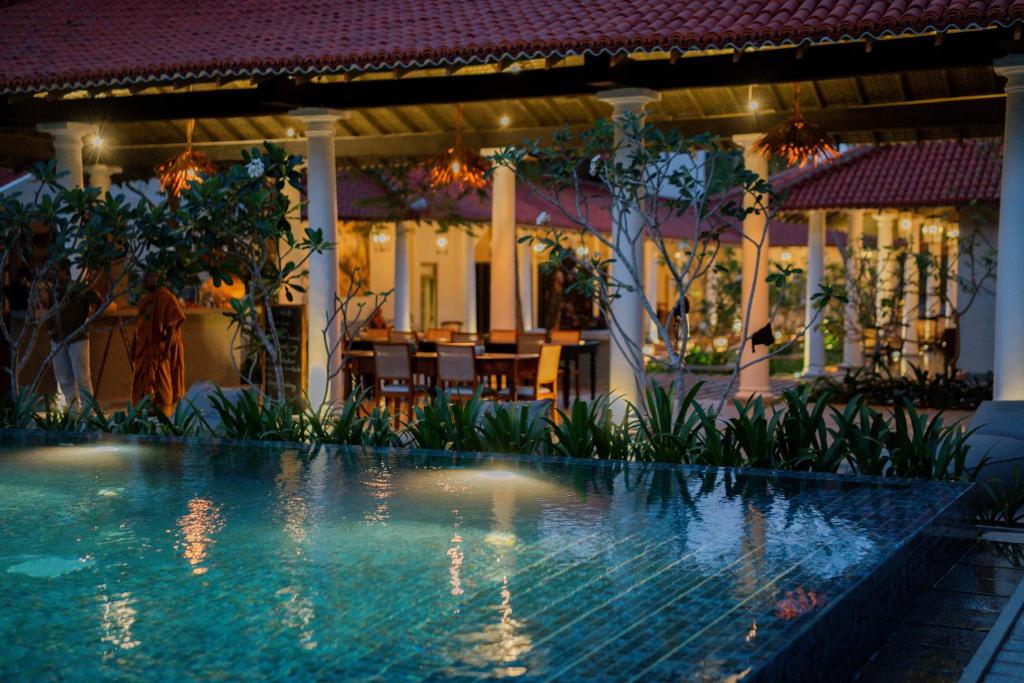 a swimming pool in front of a house at night at Rekawa Wellness Resort in Tangalle