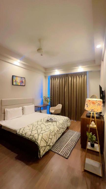 a bedroom with a bed and a chair and a desk at Skycabinomaxe in Greater Noida