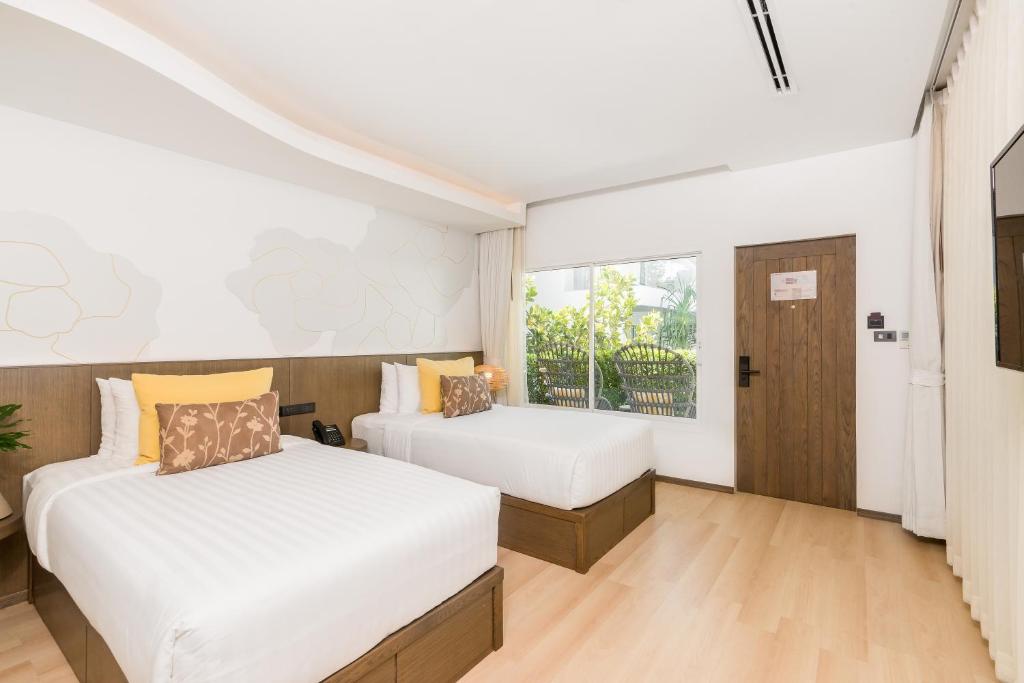 a bedroom with two beds and a window at La Vida Samui in Chaweng