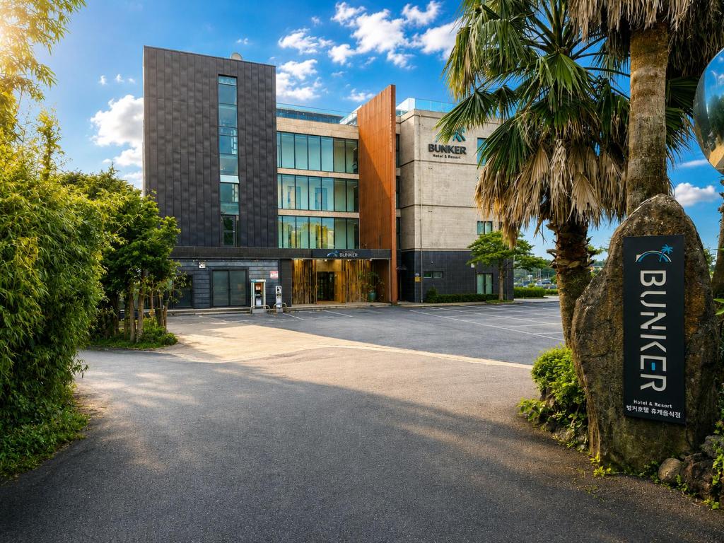 a building with a palm tree in front of it at Jeju BunkerHotel&Resort in Seogwipo
