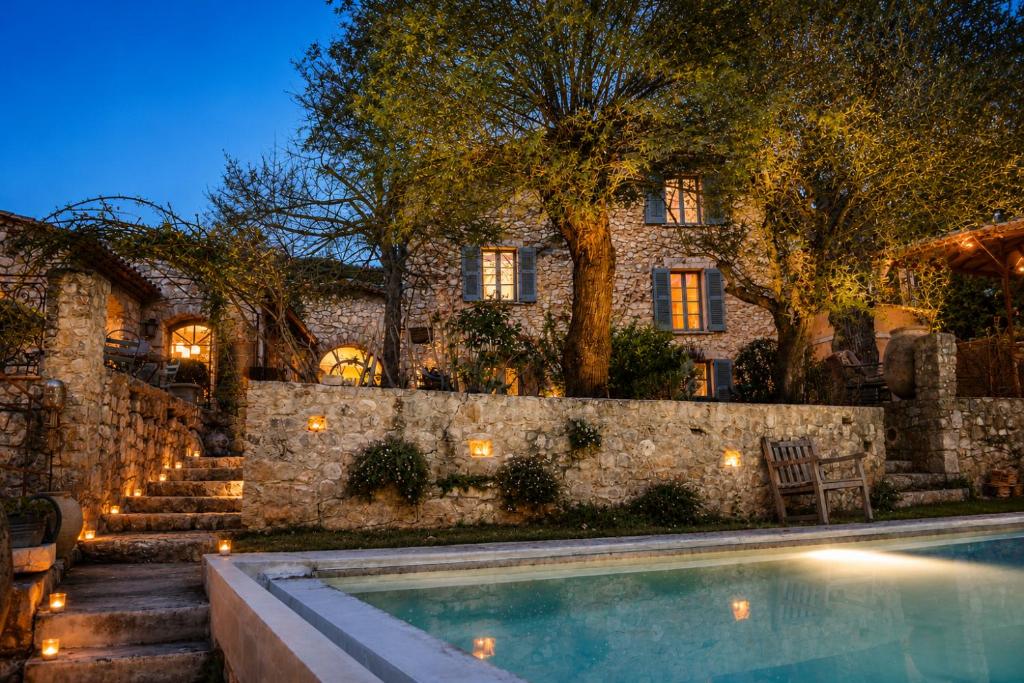 a house with a swimming pool and a stone wall at Les Rosées in Mougins