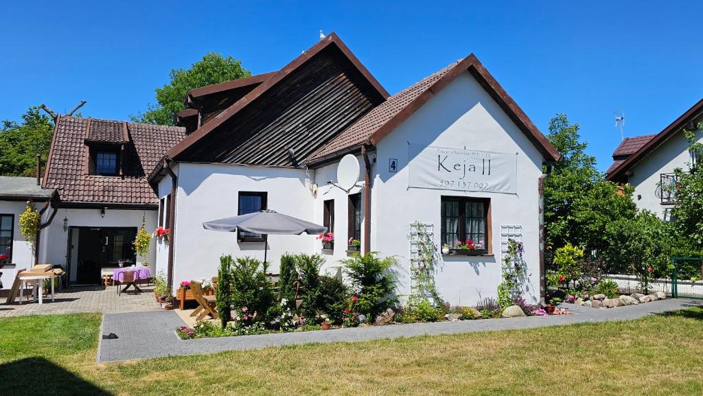 a white house with an umbrella in a yard at Keja II in Łeba