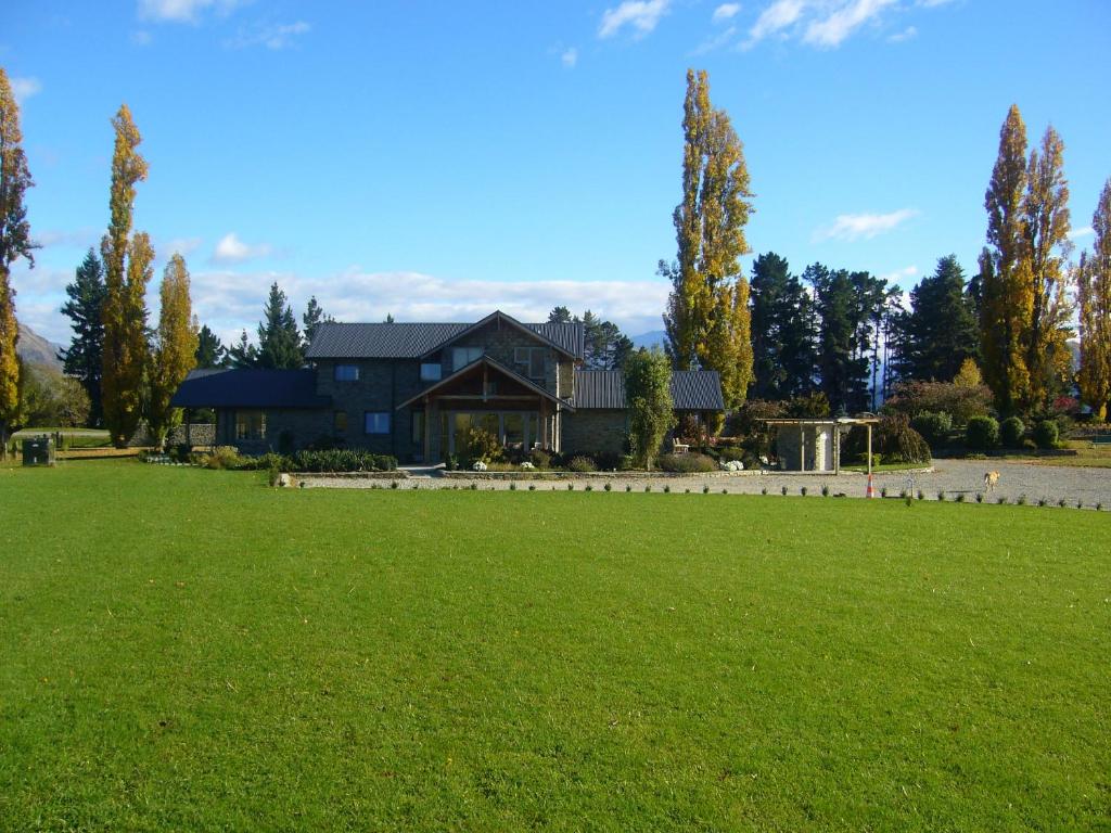 una casa con un césped verde delante de ella en Golfcourse Road Chalets and Lodge, en Wanaka